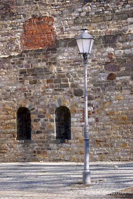 Alte Straßenlampe vor einer Klostermauer in Magdeburg.